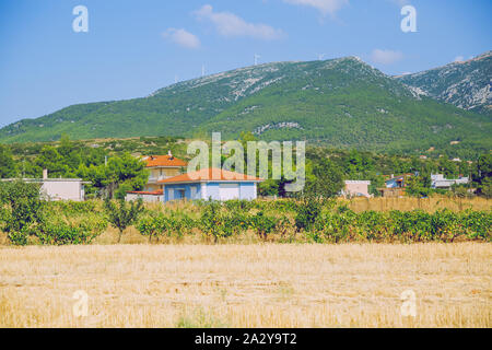République grecque. Les champs et les montagnes, l'herbe et des maisons. Au loin les montagnes et ciel. 12. Septembre 2019. Banque D'Images