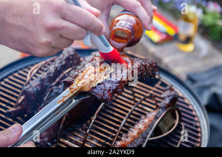 Côtes levées marinées de cuisson sur un barbecue en plein air Banque D'Images