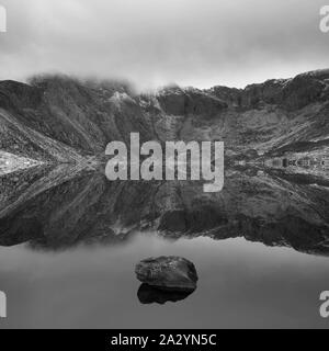 Superbe paysage d'hiver spectaculaire image de Llyn Idwal et sommets de montagnes de Snowdonia en Glyders en noir et blanc Banque D'Images