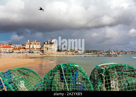 Promenade en bord de mer avec des filets de pêche, et Praia da Ribeira beach ou la plage Praia dos Pescadores sur le front de mer de Cascais, station balnéaire populaire au Portugal. Banque D'Images