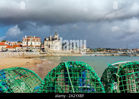 Promenade en bord de mer avec des filets de pêche, et Praia da Ribeira beach ou la plage Praia dos Pescadores sur le front de mer de Cascais, station balnéaire populaire au Portugal. Banque D'Images