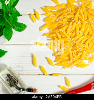 Pâtes penne, vert basilic, parmesan, le sésame, l'Ail, piment, les œufs se trouvent sur un arbre blanc tableau Banque D'Images