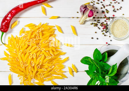 Pâtes penne, vert basilic, parmesan, le sésame, l'Ail, piment, les œufs se trouvent sur un arbre blanc tableau Banque D'Images