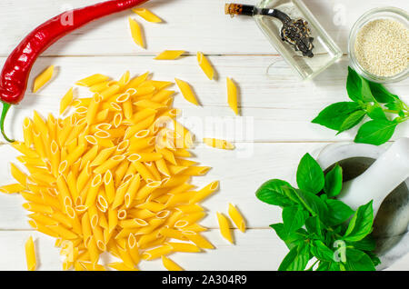 Pâtes penne, vert basilic, parmesan, le sésame, l'Ail, piment, les œufs se trouvent sur un arbre blanc tableau Banque D'Images