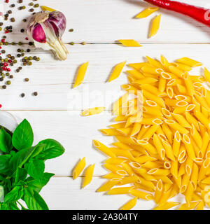 Pâtes penne, vert basilic, parmesan, le sésame, l'Ail, piment, les œufs se trouvent sur un arbre blanc tableau Banque D'Images