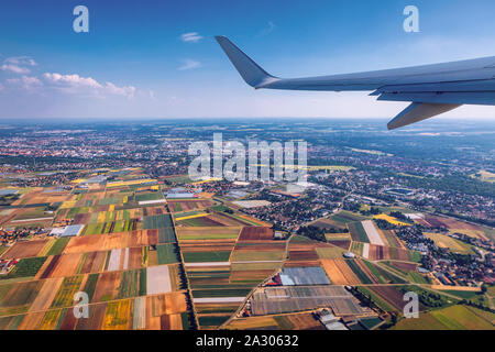 Airplane windows afficher au-dessus de la terre sur le monument vers le bas. Vue depuis la fenêtre d'un avion sur une aile vol au-dessus de terres agricoles et les champs. Voir à partir de win Banque D'Images