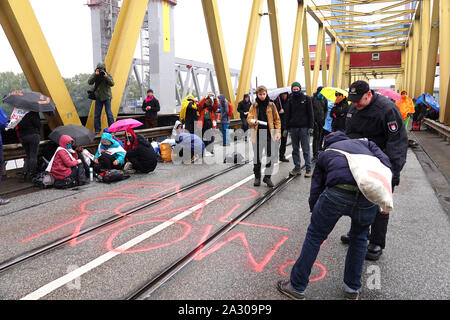 04 octobre 2019, Hambourg : activistes du climat d'écrire les mots "charbon fin maintenant !' avec de la craie pulvérisée sur la chaussée de l'Kattwyk pont. Une centaine d'activistes du climat ont occupé le Kattwyk pont dans le port de Hambourg et paralysé la circulation pendant plusieurs heures. Sous la devise 'eCOALonize l'Europe", ils ont exigé le retrait immédiat de lignite et de la houille ainsi que la fermeture de toutes les centrales au charbon dans le port de Hambourg et du charbon à Hambourg. (Dpa 'protester contre une centrale à charbon Moorburg jusqu'- les militantes occupent bridge') Photo : Magdalena Tröndle/dpa Banque D'Images