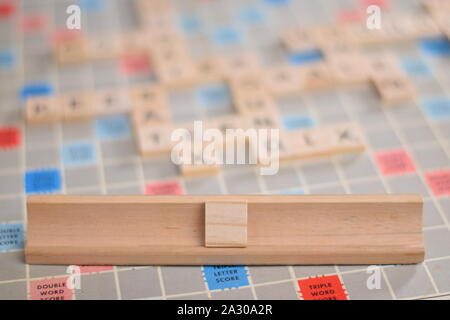 Scrabble en bois blanc 1 tuile sur une tuile-rack, que vous pouvez remplir dans votre propre mot. Dans l'arrière-plan une carte vintage, des problèmes de mise au point, avec copie espace Banque D'Images