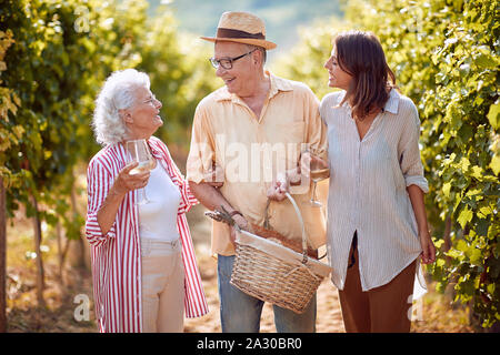 Happy Family toasting et boire du vin et s'amuser en plein air. Campagne ancienne vigne. Banque D'Images