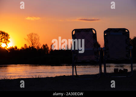 Deux fauteuils se tenir sur la rive de la rivière dans le contexte de l'endroit romantique au coucher du soleil Banque D'Images