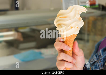 Jeune femme tenant un cornet de crème glacée Cornish fouettée juste acheté dans une boutique à Mevagissey Cornwall icecream Banque D'Images