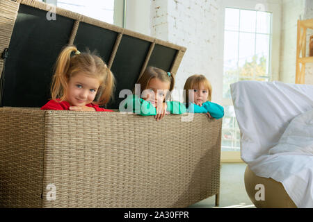 Les petites filles en pyjama doux et chaleureux de jouer à la maison. Des enfants de race blanche dans des vêtements colorés s'amuser ensemble. L'enfance, l'accueil confort, bonheur. Assis dans une grande boîte en osier et laughting. Banque D'Images