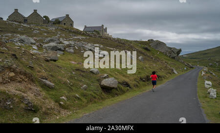 Vue arrière du woman jogging sur la route, l'île d'Achill, Comté de Mayo, Irlande Banque D'Images