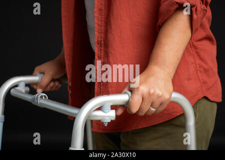 Close-up of African woman holding pour Walker et essayant de marcher sur fond noir Banque D'Images