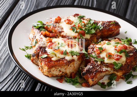 Côtelettes de porc frit épicé avec bacon et fromage fondu libre sur une plaque sur la table horizontale. Banque D'Images