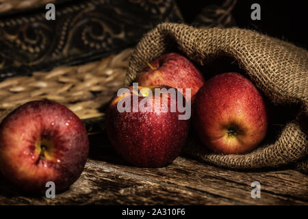 Pommes rouges frais sur table rustique en bois avec fond de jute. Banque D'Images