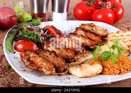 Ailes de poulet rôti servi sur une plaque blanche avec des poivrons tomates oignons et salades Banque D'Images