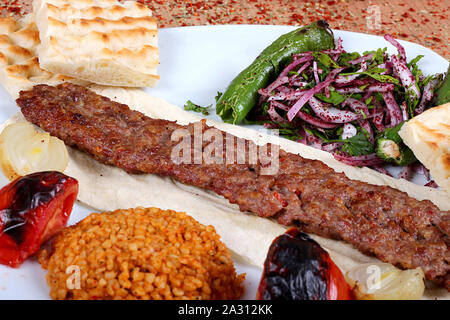 Un service complet de l'ORFA de style turc kebab complet avec le poivre vert et légumes frais sur une table remplie d'épices épicé close-up Banque D'Images