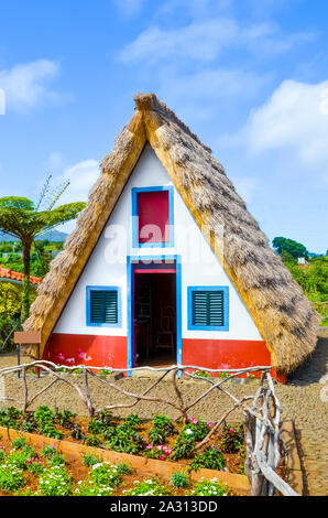 Ancienne maison traditionnelle dans la région de Santana, l'île de Madère, au Portugal. Sol en bois, petite, triangulaire et maisons colorées représentent une partie du patrimoine de Madère. Petit jardin à l'avant. Bâtiment historique, lieu touristique. Banque D'Images