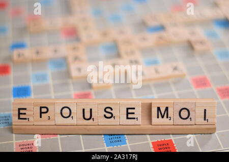 Le mot français "epouse moi" (en anglais : 'marry me') en tuiles de SCRABBLE en bois sur une grille. L'arrière-plan une carte vintage, des problèmes de mise au point, copy space Banque D'Images