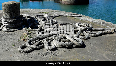 Vieux bollard et corde à un port côtier Banque D'Images