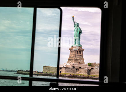 La Statue de la liberté vue à travers une fenêtre dans le ferry, New York City, USA. Banque D'Images