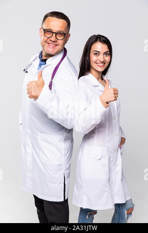 Portrait de deux médecins en blouse blanche et verres showing thumb-up against white background Banque D'Images