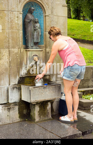 Femme personne chargée de remplir ses propres conteneurs de bouteilles en plastique avec de l'eau de source de Buxton St Anne's bien dans la ville thermale de Buxton Derbyshire, Angleterre Banque D'Images