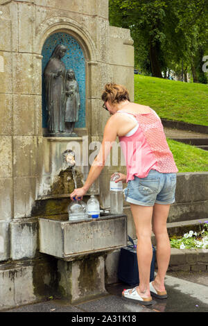 Femme personne chargée de remplir ses propres conteneurs de bouteilles en plastique avec de l'eau de source de Buxton St Anne's bien dans la ville thermale de Buxton Derbyshire, Angleterre Banque D'Images