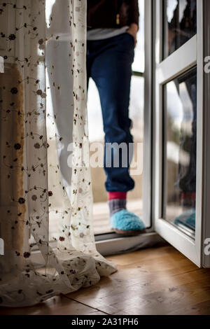 Une porte ouverte (PVC) avec accès au balcon, à côté d'un magnifique tulle, en arrière-plan un homme entre dans la chambre. Banque D'Images