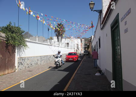 Rue Grand-angle de vue moto blanche et rouge voiture dans la rue dans le village canarien d'Arona. La journée de célébration du patrimoine. Sept 2019. Banque D'Images