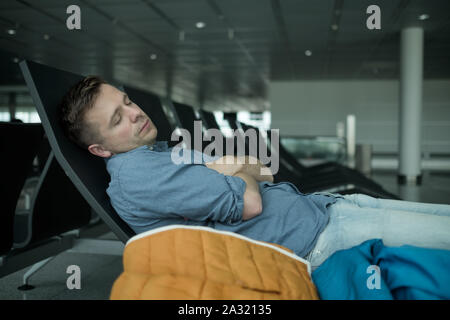 Homme mûr dans l'aéroport de dormir sur un banc Banque D'Images