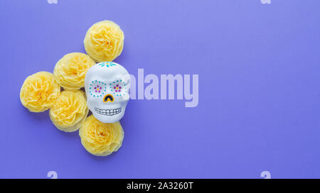 Crâne mexicain avec des fleurs jaunes de papier sur fond violet chargés. Le Jour des Morts. Banque D'Images