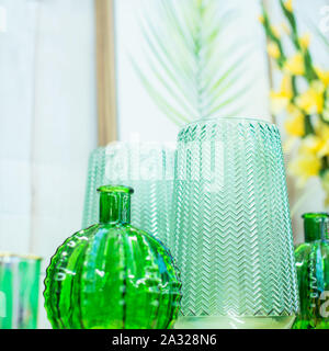 Close up composition de vases en verre vert clair, l'affiche avec des feuilles tropicales sur le fond blanc. Style scandinave moderne de design d'intérieur Banque D'Images