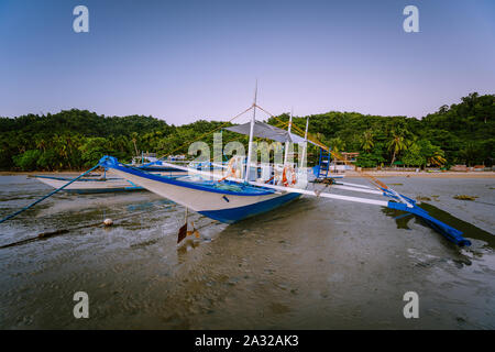 Les Philippines's Banca bateau. Bateau de pêche traditionnel sur la plage à marée basse dans la lumière du soir. El Nido, Palawan Banque D'Images