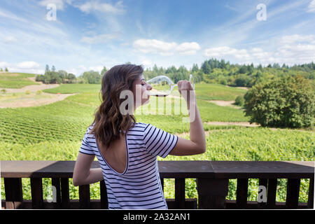 Jolie jeune femme brune à une belle cave avec un verre de vin rouge. Banque D'Images