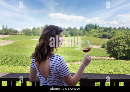 Jolie jeune femme brune à une belle cave avec un verre de vin rouge. Banque D'Images