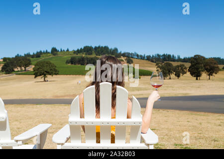 Jolie jeune femme brune à une belle cave avec un verre de vin rouge. Banque D'Images