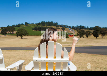 Jolie jeune femme brune à une belle cave avec un verre de vin rouge. Banque D'Images