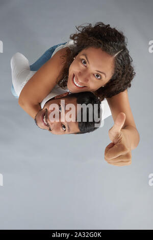 Young woman showing thumb up au-dessus vu de dessus en arrière-plan couleur gris studio Banque D'Images