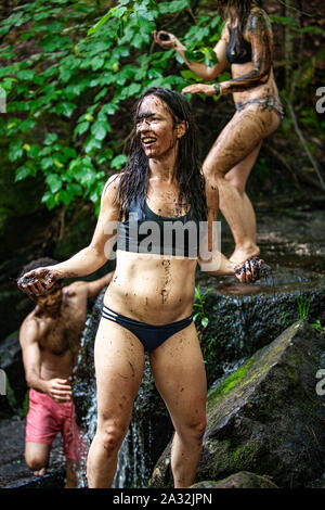 Un groupe mixte de free spirited people sont vus le bain et le lavage dans un fleuve sacré au cours d'une retraite à l'esprit ludique, de jeter de la boue et s'amusant. Banque D'Images