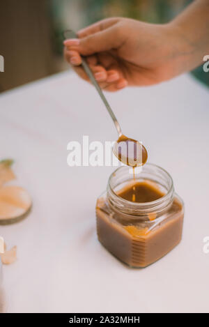 Caramel liquide brun salé fait maison. Caramel mou maison faite à partir de sucre sur un fond de pommes et de citrouilles. Banque D'Images