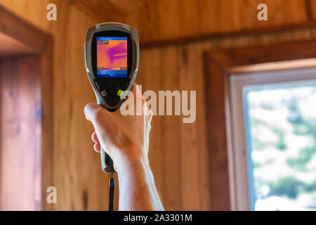 Une vue en gros plan sur la lunette arrière d'une caméra thermovision infrarouge dans la main d'un inspecteur, en direction de spot de plafond résidentiel dans la chaleur. Banque D'Images