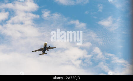 Jetliner à basse altitude avec des nuages et ciel bleu en arrière-plan Banque D'Images