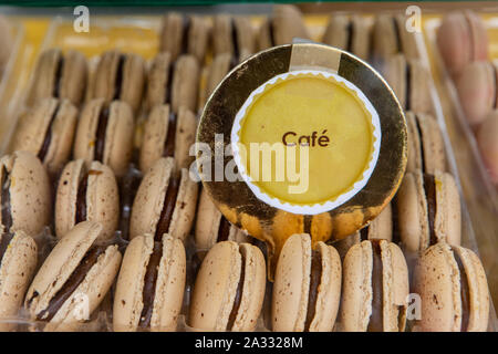 Une vue rapprochée de la lumière de couleur brune à saveur de café macarons français sur un stand avec un petit signe français sur un décrochage lors d'un marché fermier local. Banque D'Images