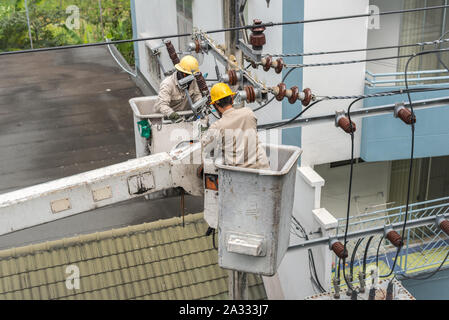 Electriciens à l'uniforme sont la fixation d'une ligne électrique, d'être sur des plates-formes élévatrices d'un camion de réparation. Banque D'Images