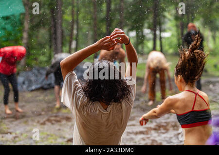 Un groupe important d'hommes et femmes d'expérience consciente de la danse et de la méditation dans la boue du défrichement des terres forestières au cours d'une nature retreat. Banque D'Images