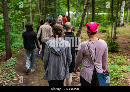 Un grand groupe de personnes de plusieurs générations sont vus de dos, marchant ensemble le long d'un sentier forestier au cours d'une société multiculturelle et autochtone en retraite la nature. Banque D'Images