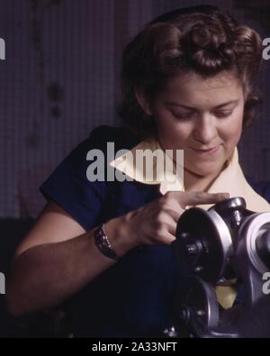 Détail du visage, une jeune femme employée de North American Aviation, Incorporated, travaillant sur le mécanisme d'atterrissage d'un avion de chasse P-51, Inglewood, Californie (rognée). Banque D'Images