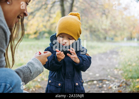 Mignon bébé garçon mode dans les tenues de explore le monde avec la mère à l'automne nature park Banque D'Images